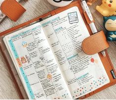 an open planner book sitting on top of a table next to a cup and other items