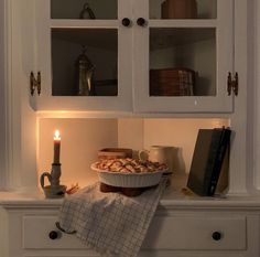 a candle is lit in the corner of a cabinet with some food on it and other items