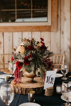 a centerpiece with flowers and greenery on a table