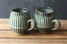 two green mugs sitting on top of a wooden table