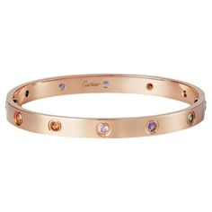 The 18k rose gold 10 multi-gem set Love bangle bracelet by Cartier is a true testament to the brand's exquisite craftsmanship and iconic design. This stunning bangle is adorned with a vibrant array of gemstones, including yellow and pink sapphires, green and orange garnets, and amethysts, creating a kaleidoscope of colors that captures the eye. Each gemstone is meticulously set in a rubover setting, ensuring their brilliance and allowing them to shine from every angle. The combination of rose gold and the vivid gemstones creates a captivating and harmonious contrast, resulting in a piece that exudes elegance and sophistication. This Love bangle is not only a beautiful accessory but also a symbol of commitment and enduring love. It comes complete with a screwdriver, allowing for easy and se Jewellery Cartier, Bracelets Cartier, Cartier Bangle, Cartier Jewellery, Garnet Jewellery, Amethyst Jewellery, Pink Gold Jewelry, Jewelry Cartier, Sapphire Bangle