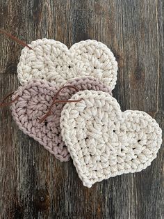 two crocheted hearts sitting on top of a wooden table