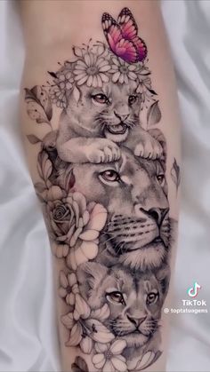 a woman's leg with tattoos on it and two lions surrounded by flowers, butterflies and a butterfly