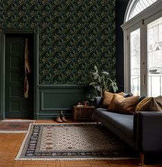 a living room filled with furniture and wallpaper covered in green leaves on the walls