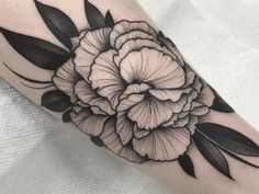 a black and white flower tattoo on the left arm, with leaves around it's edges