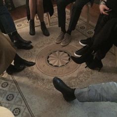 four people sitting in a circle with their feet on the ground and one person wearing black shoes