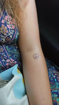 a woman with a small tattoo on her left arm and the word peace written in it