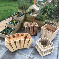 several wooden planters sitting on top of a cement floor next to grass and flowers