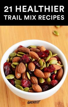 a white bowl filled with nuts and cranberries on top of a wooden table