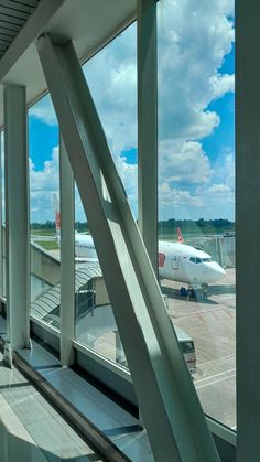 an airplane is sitting on the tarmac at the airport, as seen through large windows