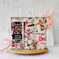 three personalized tumblers sitting on top of a wooden tray next to pink flowers