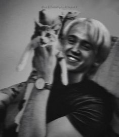 a black and white photo of a woman holding a cat up to her face while smiling