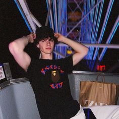 a young man sitting on top of a chair next to a bag