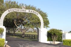 the entrance to south fork ranch is white and has a large arch over it's entrance