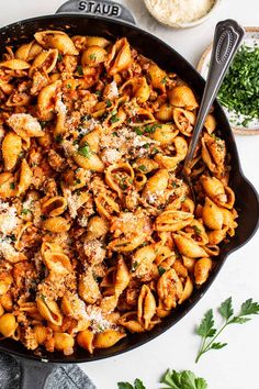 a skillet filled with pasta, meat and parmesan cheese