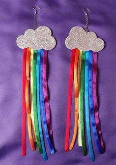 two rainbows are hanging from the side of a pair of metal earrings with clouds on them