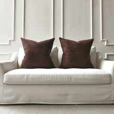 two brown pillows sitting on top of a white couch