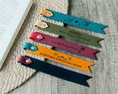 four bookmarks with the names of different authors on them, sitting next to an open book