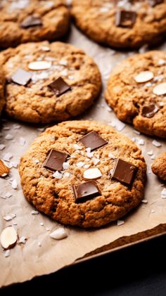 chocolate chip cookies with almonds and sea salt on a sheet of parchment paper, ready to be eaten