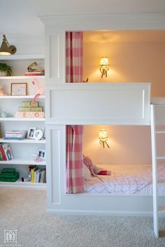 a white bunk bed sitting in a bedroom next to a book shelf filled with books