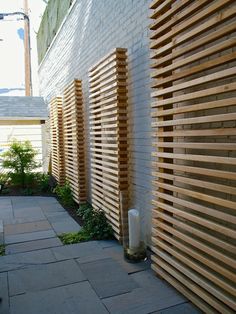 a wooden fence next to a white brick wall with plants growing on it and a fire hydrant in the corner