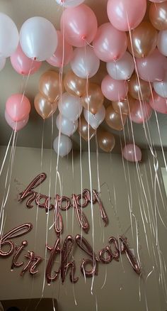 balloons and streamers in the shape of happy birthday written on a wall with helium