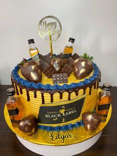 a birthday cake decorated with chocolate and caramels on the top, surrounded by liquor bottles