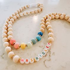 two beaded necklaces on a marble counter with the word mr and mrs spelled in small letters