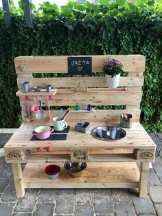 an outdoor kitchen made out of pallets and wooden planks with pots, pans and bowls on it