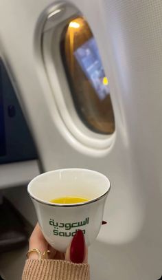 a cup of coffee in someone's hand on an airplane