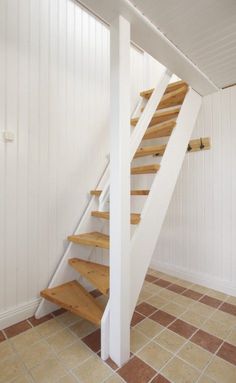 there is a stair case in the corner of this room with tile flooring and white walls