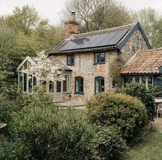 an old brick house with solar panels on the roof and windows, surrounded by greenery