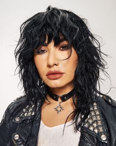 a close up of a person wearing a leather jacket and choker with stars on it