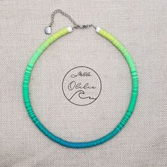 a green and blue beaded necklace on a white fabric background with the words meet me now written across it