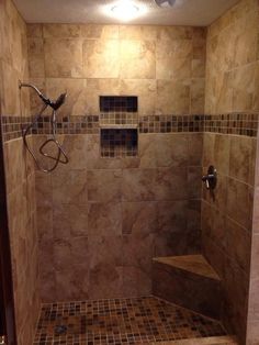 a walk in shower sitting next to a tiled wall and floor covered in brown tiles