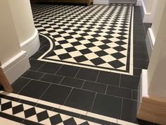 a black and white checkered tile floor in a hallway with wooden door way leading to another room