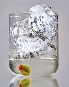 a glass filled with ice and two yellow rubber ducks sitting on it's side