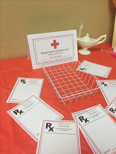 a table topped with lots of red cross cards next to a white cup and saucer