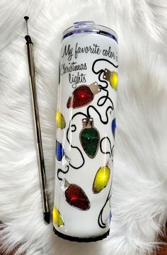 a christmas light tumbler next to a pen on top of a white fur rug