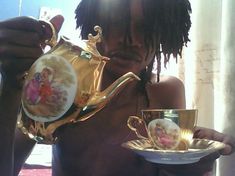 a man with dreadlocks holding a tea pot and cup