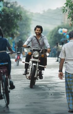 a man riding a motorcycle down a street next to other people on bicycles and motorcycles