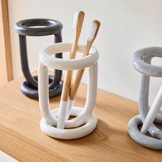 two toothbrush holders sitting on top of a wooden table