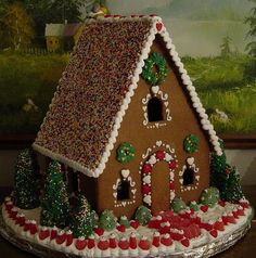 a decorated gingerbread house on display in front of a painting