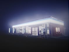 a small building sitting on the side of a road at night