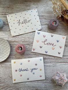 three cards with the words hello, love and thank you written on them next to some spools of thread