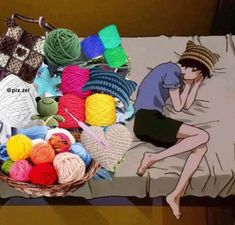 a basket filled with balls of yarn sitting on top of a bed next to a pillow