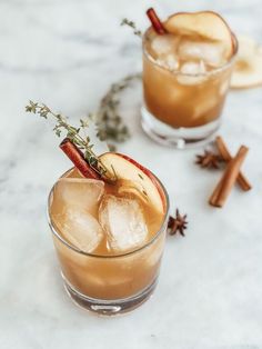 two glasses filled with apple cider cocktails on top of a marble countertop