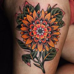 a woman's thigh with an orange and green flower tattoo on the side of her leg