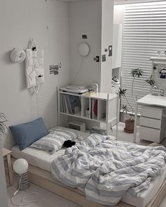 an unmade bed in a room with white walls