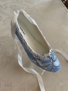 a pair of blue shoes with white lace and pearls on the bottom are sitting on a bed